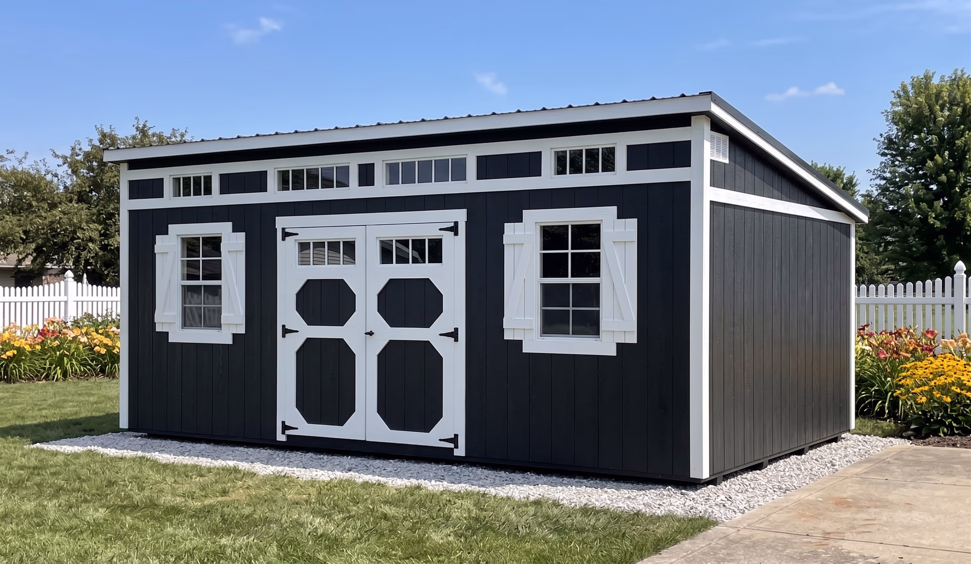 Charcoal studio shed with white trim and a row of transom windows on a gravel pad