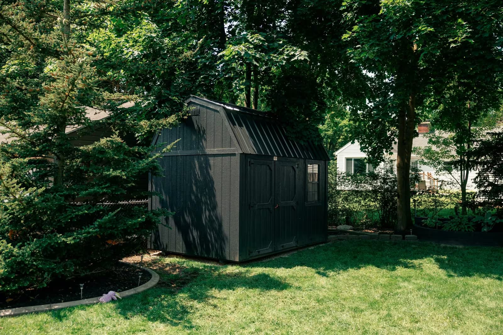 A black Amish-built barn-style shed delivered and set in a customer's backyard