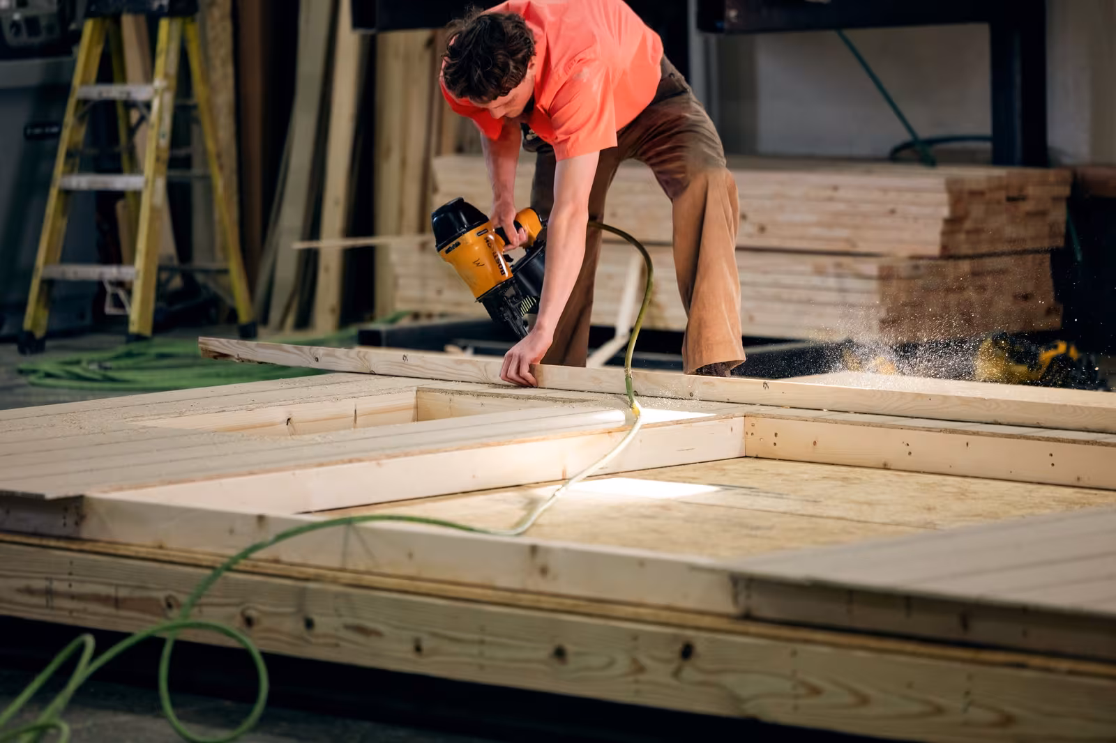 An Amish builder measuring and squaring a shed floor in the workshop