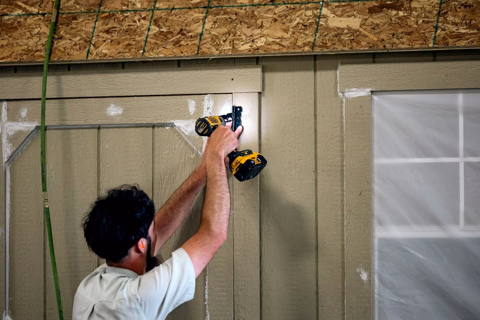 An Amish crew raising a framed wall on a shed in the workshop