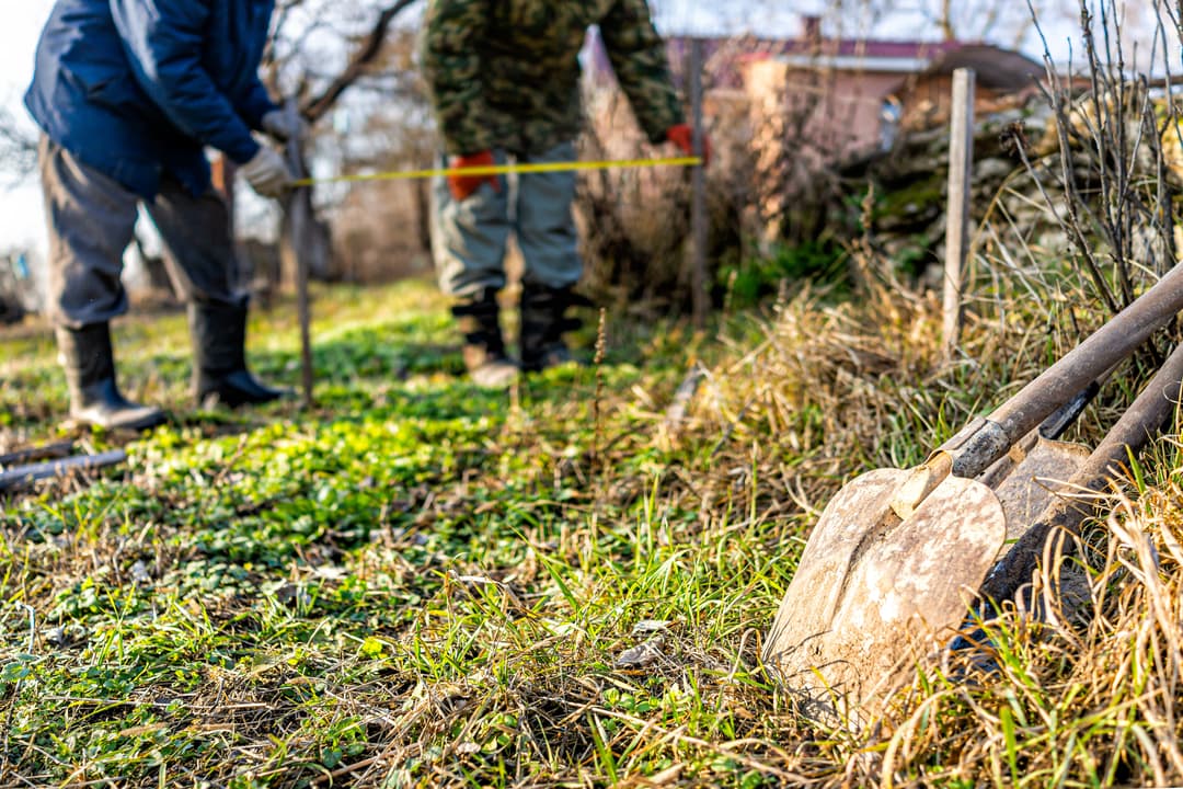 Couple measuring outdoor space for shed site planning