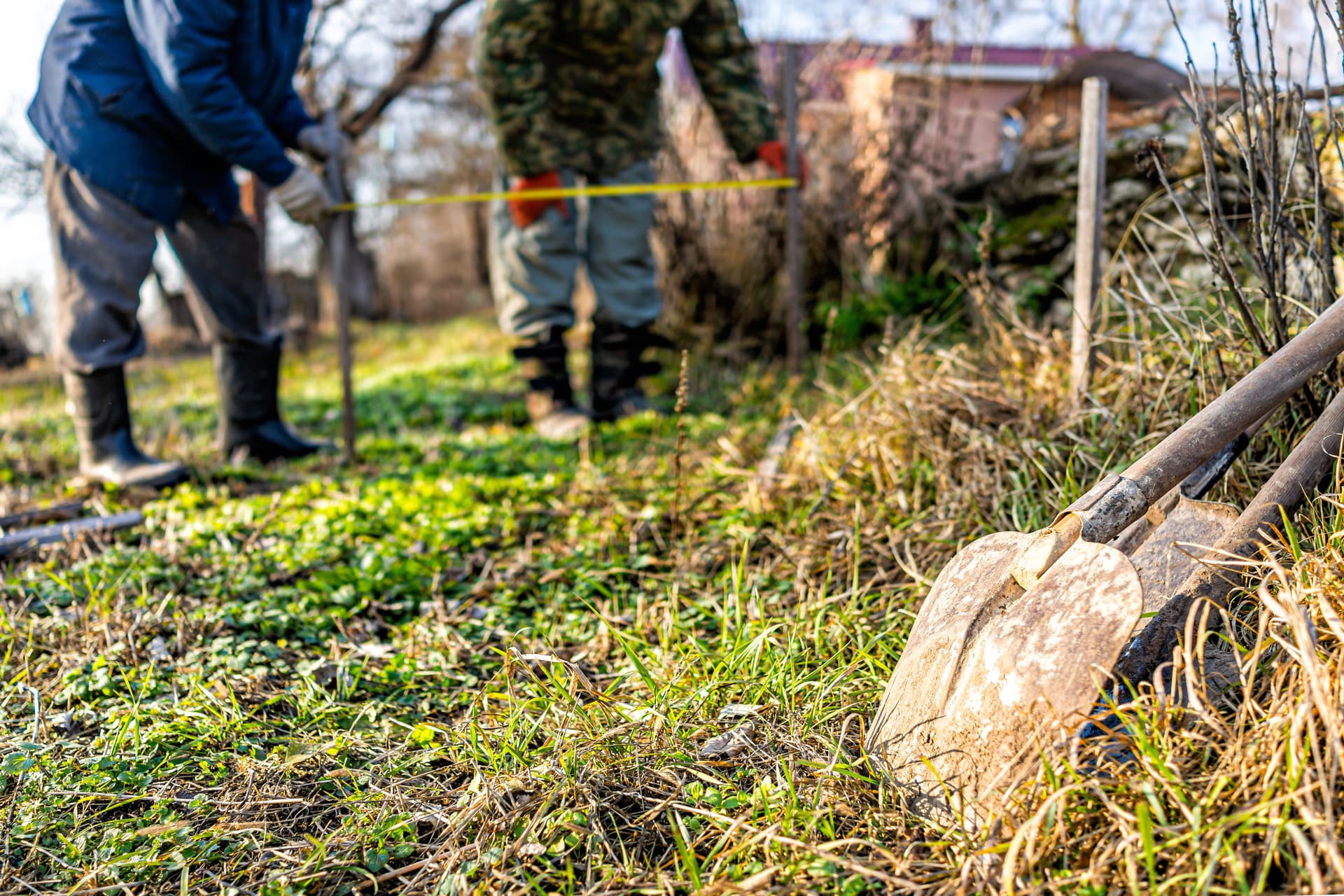Couple measuring outdoor space for shed site planning