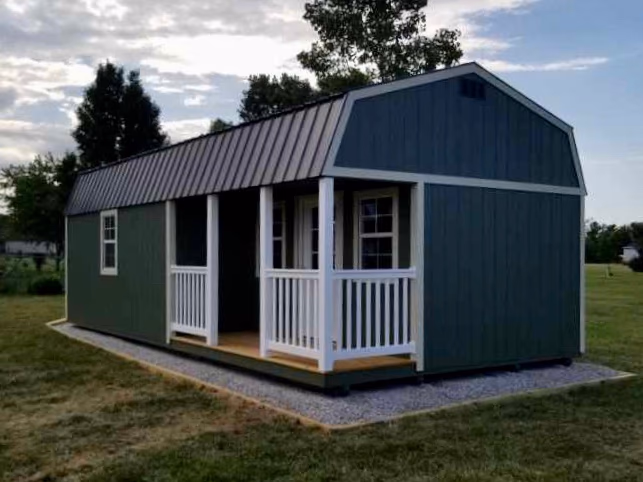 A green lofted casita with a porch on a gravel pad