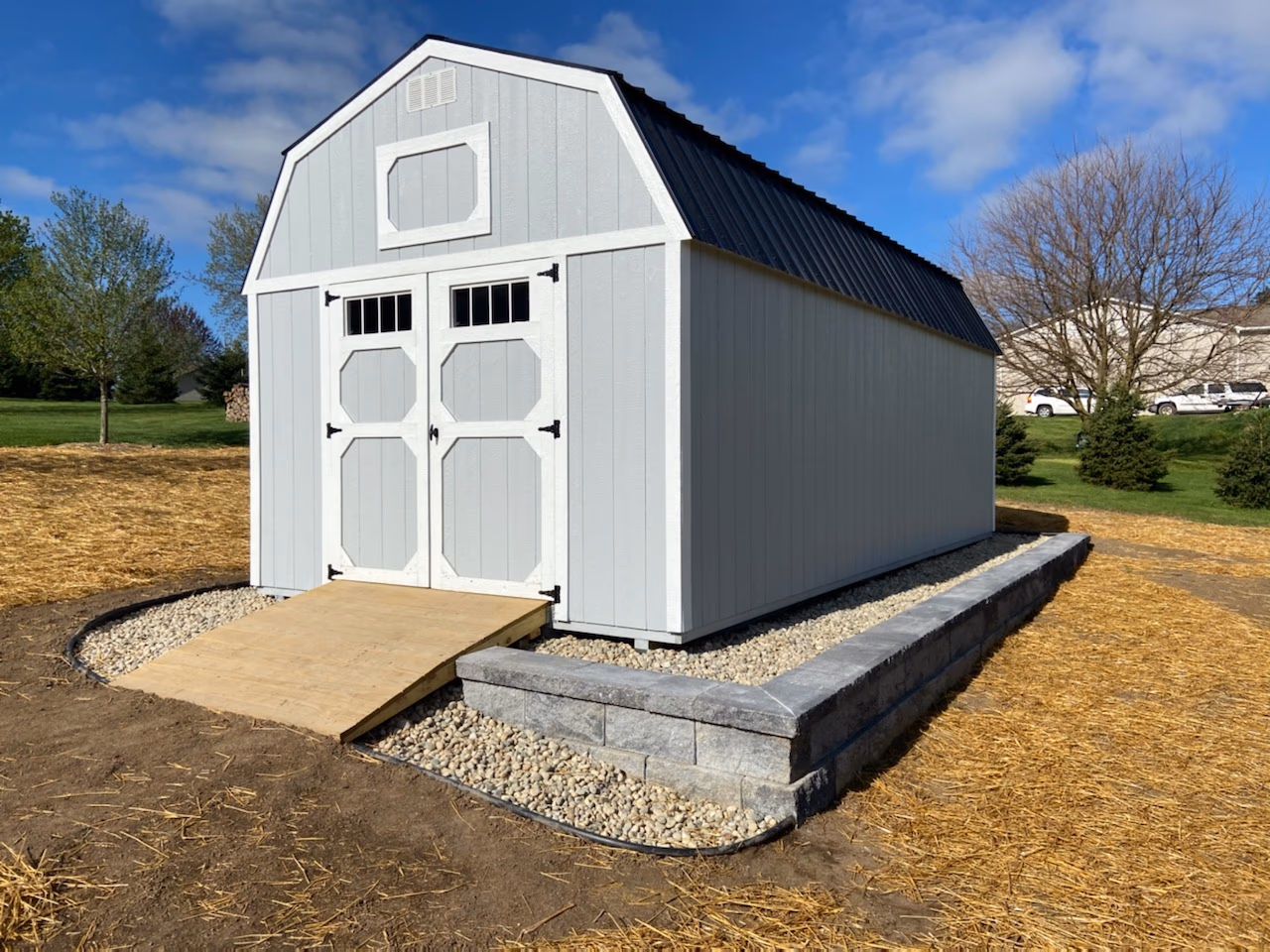 A white lofted barn on a gravel pad edged with a block wall
